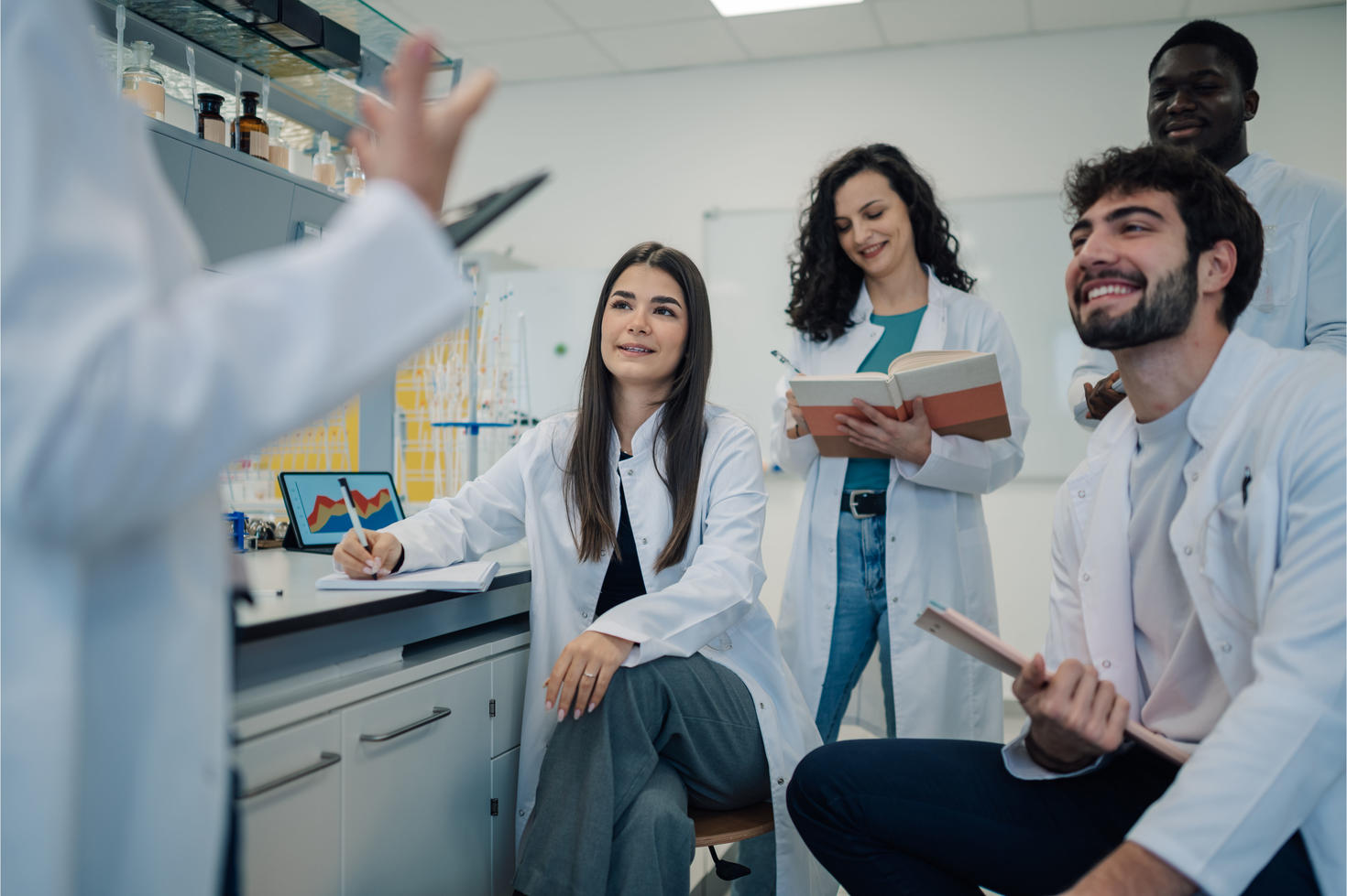 Les apprenants sont debout ou assis dans un laboratoire moderne, à l'écoute d'un formateur