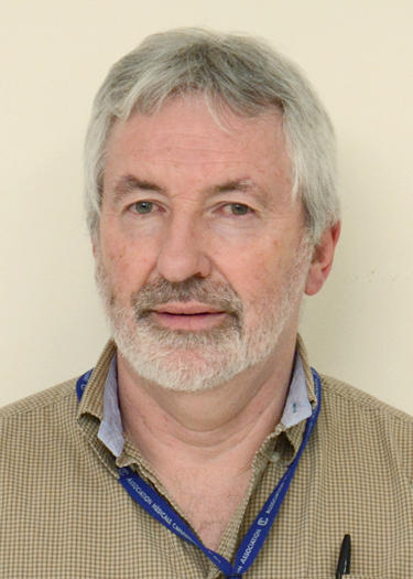 Le Dr Eoghan O’Shea sourit à la caméra; il porte une chemise beige et un cordon bleu.