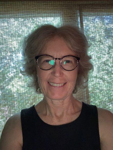 Dre Laura Muldoon, vêtue d'un t-shirt noir et portant des lunettes, sourit devant une fenêtre