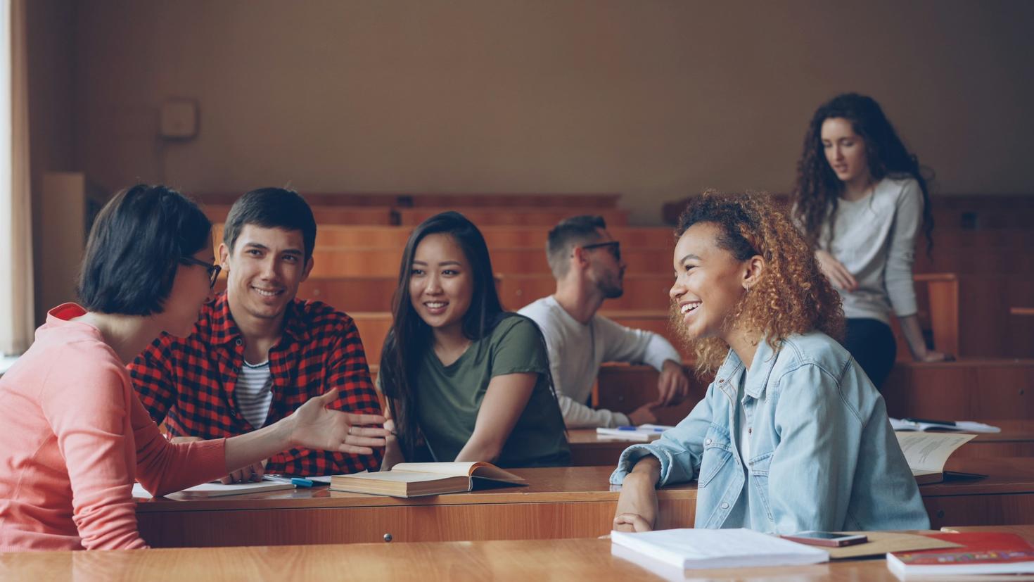 Des personnes étudiantes souriantes discutent et rient ensemble dans un amphithéâtre universitaire