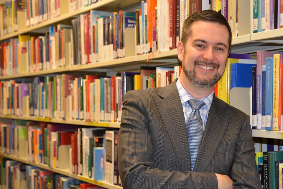 Dr Ian Colman debout dans une bibliothèque.