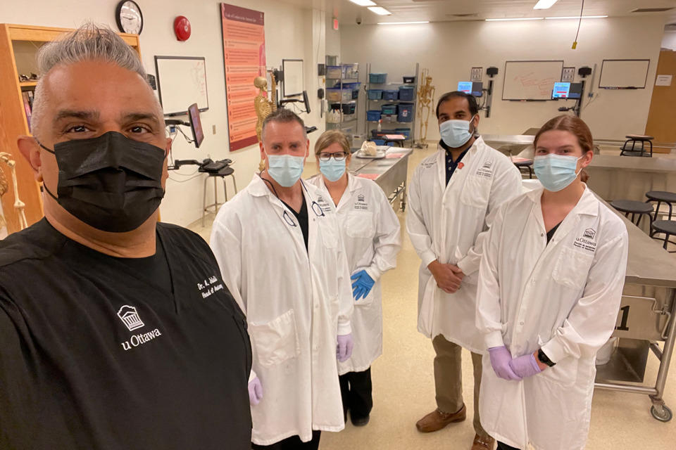 Cinq personnes en blouse de laboratoire se tiennent dans un laboratoire d'anatomie