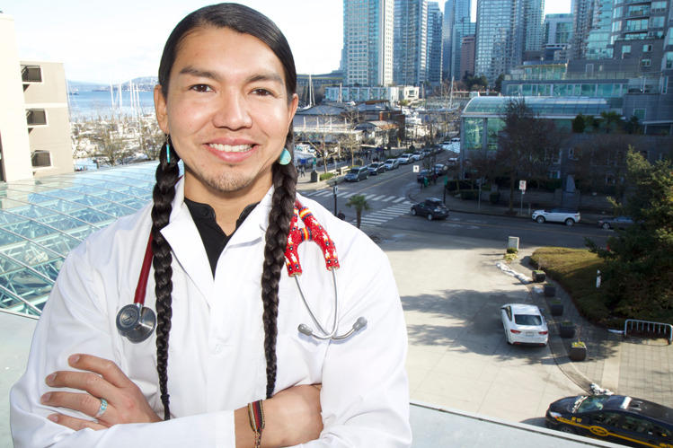 Un médecin se tient devant une fenêtre avec vue sur une ville.