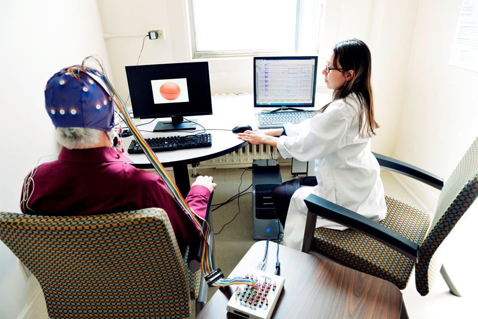 Docteure et patient portant un casque de capteurs devant un écran d'ordinateur