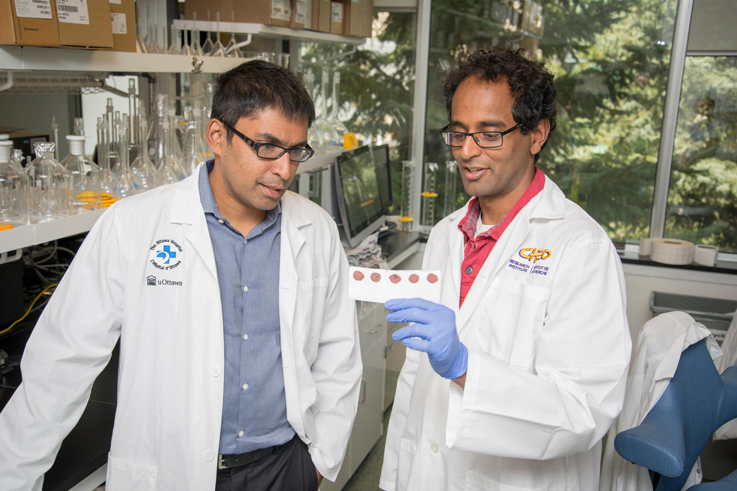 Photo des Drs Kumanan Wilson et Pranesh Chakraborty examinant un échantillon de sang.