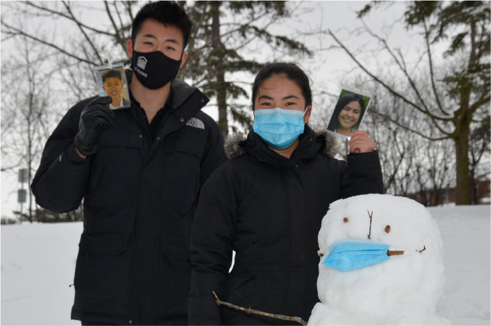 Hui Yan et Jason Tran a coté d'un bonhomme de neige, tous portant des masques