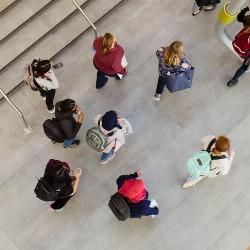 group of people standing and talking in an open indoor space, viewed from above.