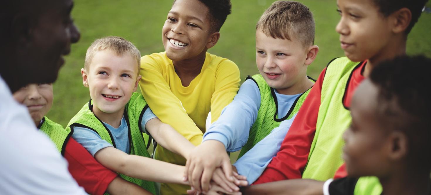 Kids putting their hands together in a huddle