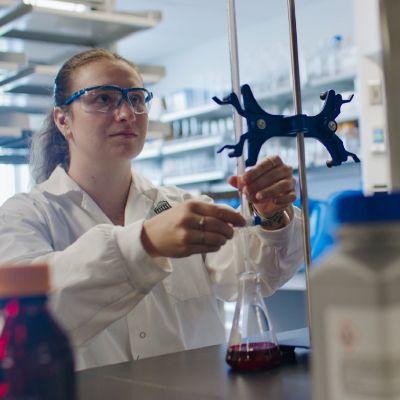 une femme travaillant dans un laboratoire avec un bécher et des lunettess de protection