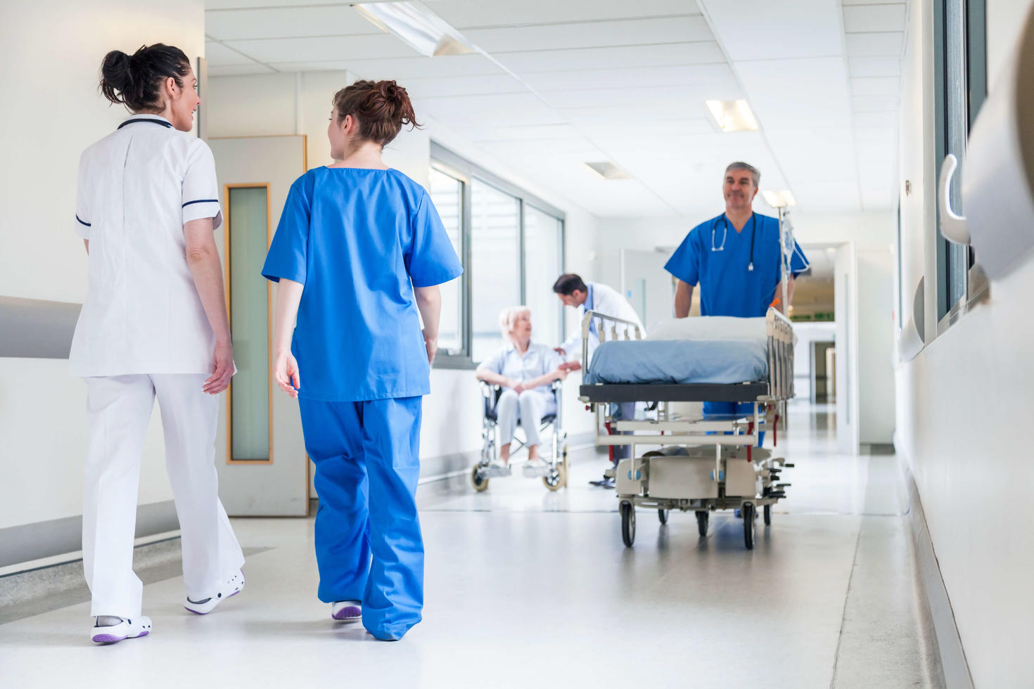 Des professionnels de santé dans un couloir d’hôpital, un brancard en mouvement.