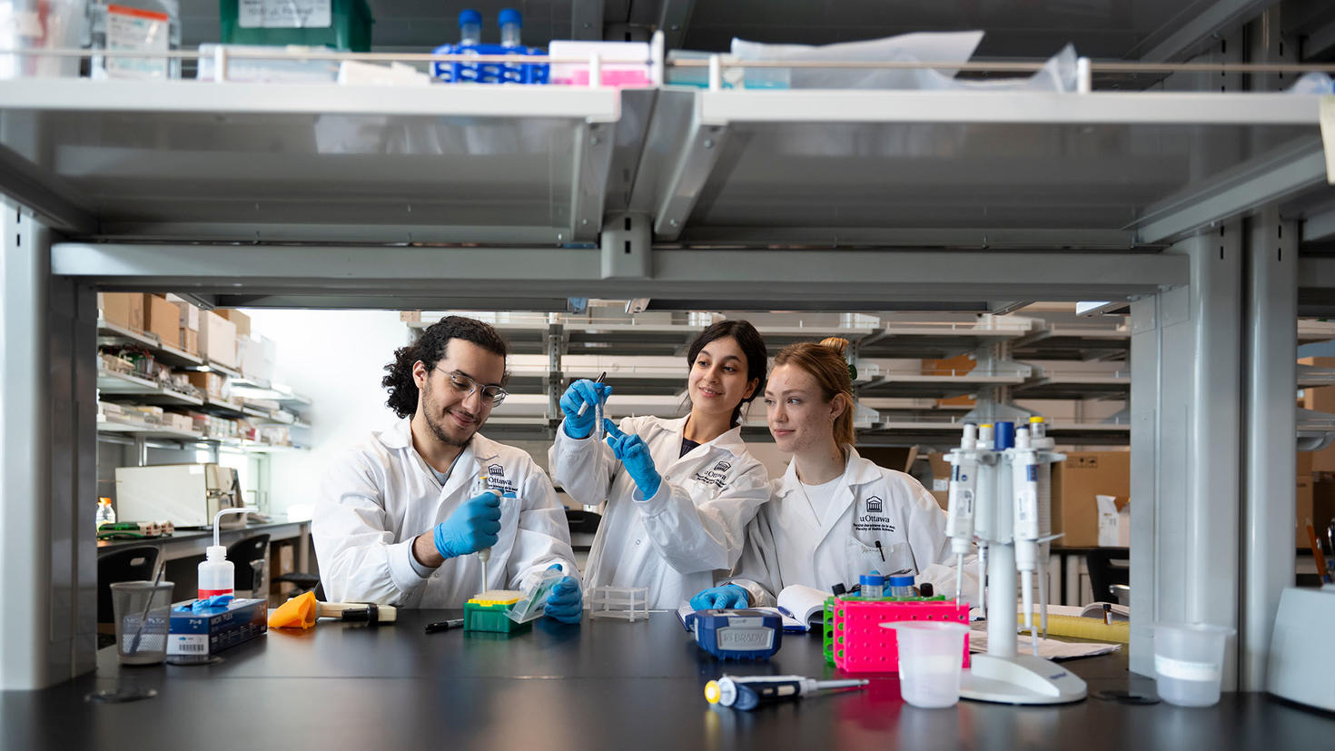 Un étudiant et deux étudiantes faisant une expérience dans un laboratoire