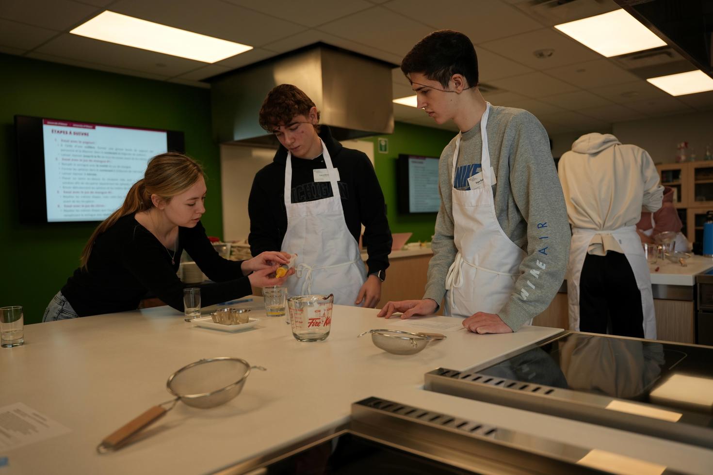 Des étudiantes et étudiant en tablier préparant des ingrédients dans un laboratoire culinaire éducatif