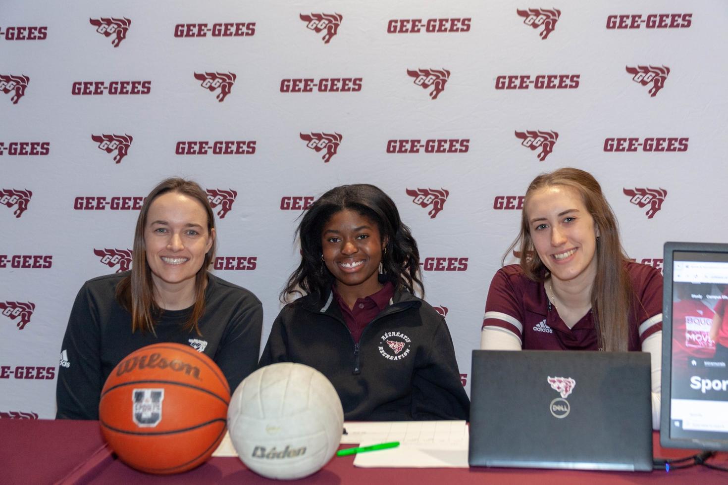 trois femmes souriantes sont assises à une table lors d'un événement sportif