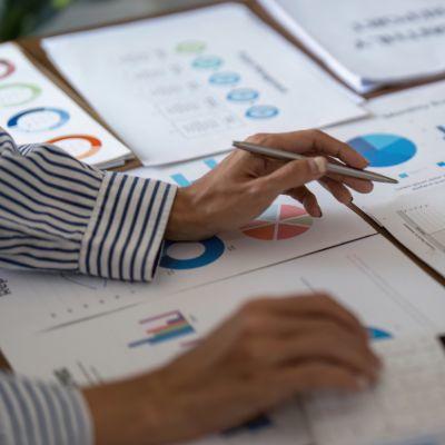 Gros plan des mains d'une femme avec des graphiques sur du papier sur une table