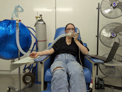 Une femme s'assoit sur une chaise tandis que des machines testent son taux d'oxygène.