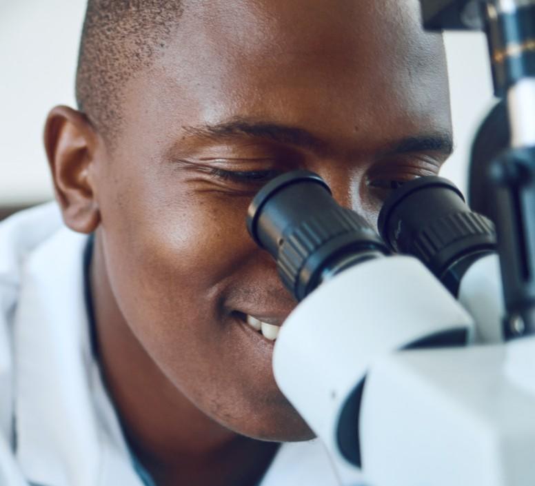 Homme souriant en regardant à travers un microscope