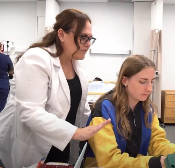 Une scientifique guide une étudiante en laboratoire.