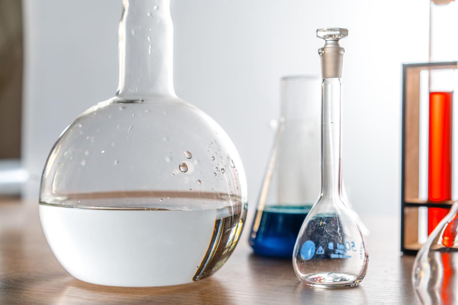 Verrerie de laboratoire assortie contenant des solutions expérimentales, posée sur une surface en bois.