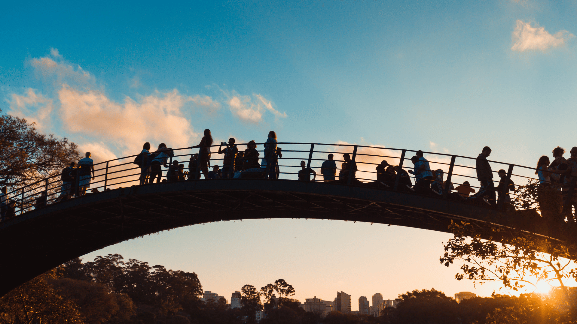 Silhouettes de personnes sur un pont au coucher du soleil