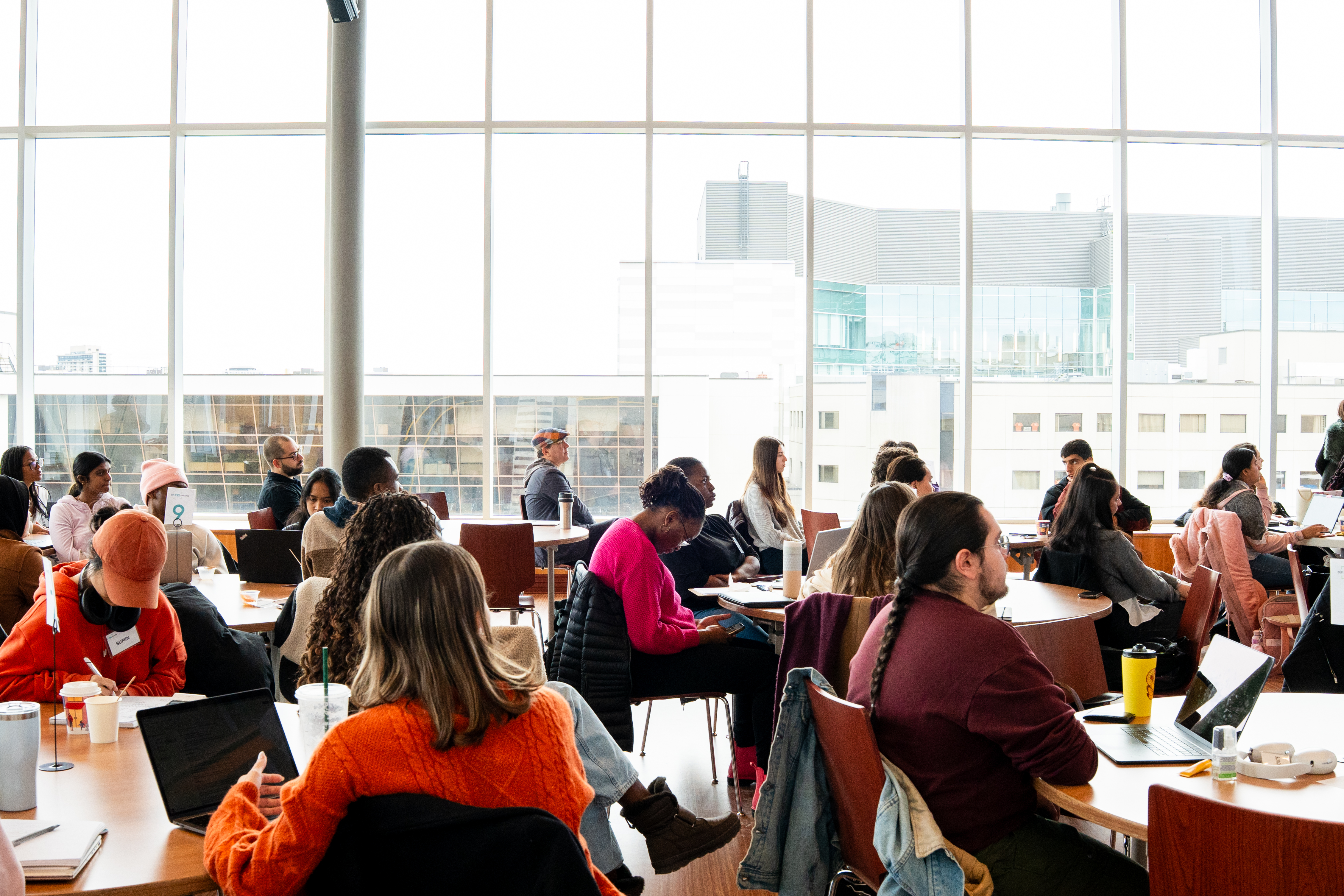 Étudiants participant à une séance d’apprentissage collaborative dans une salle de classe lumineuse, avec ordinateurs portables et discussions en groupe.