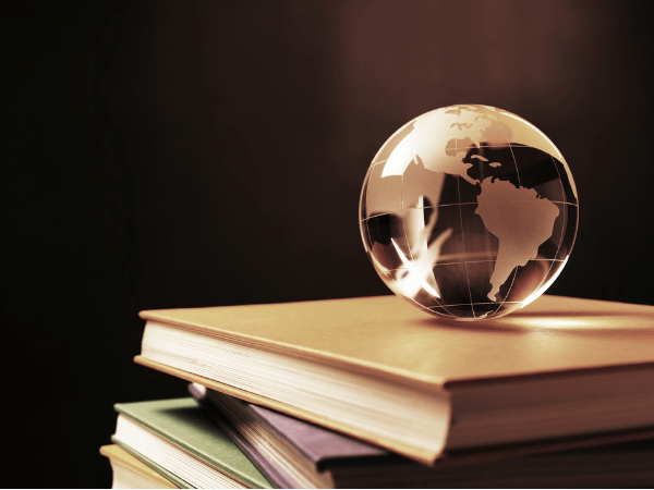 La photo d'un petit globe transparent posé sur une pile de livres.