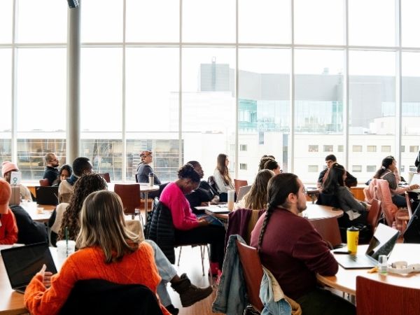 Étudiants participant à une séance d’apprentissage collaborative dans une salle de classe lumineuse, avec ordinateurs portables et discussions en groupe.
