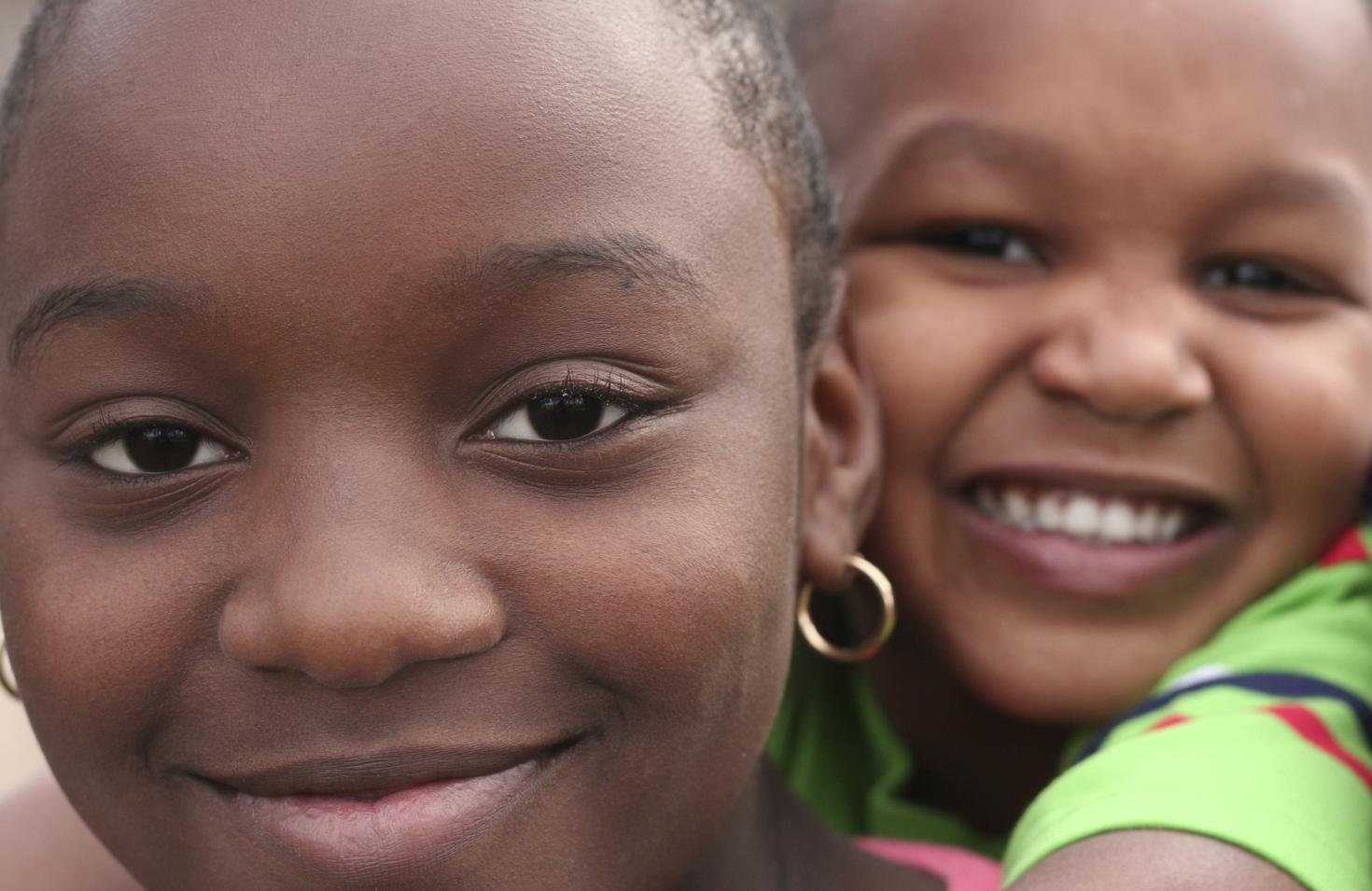 Deux enfants se serrent dans leurs bras en souriant.