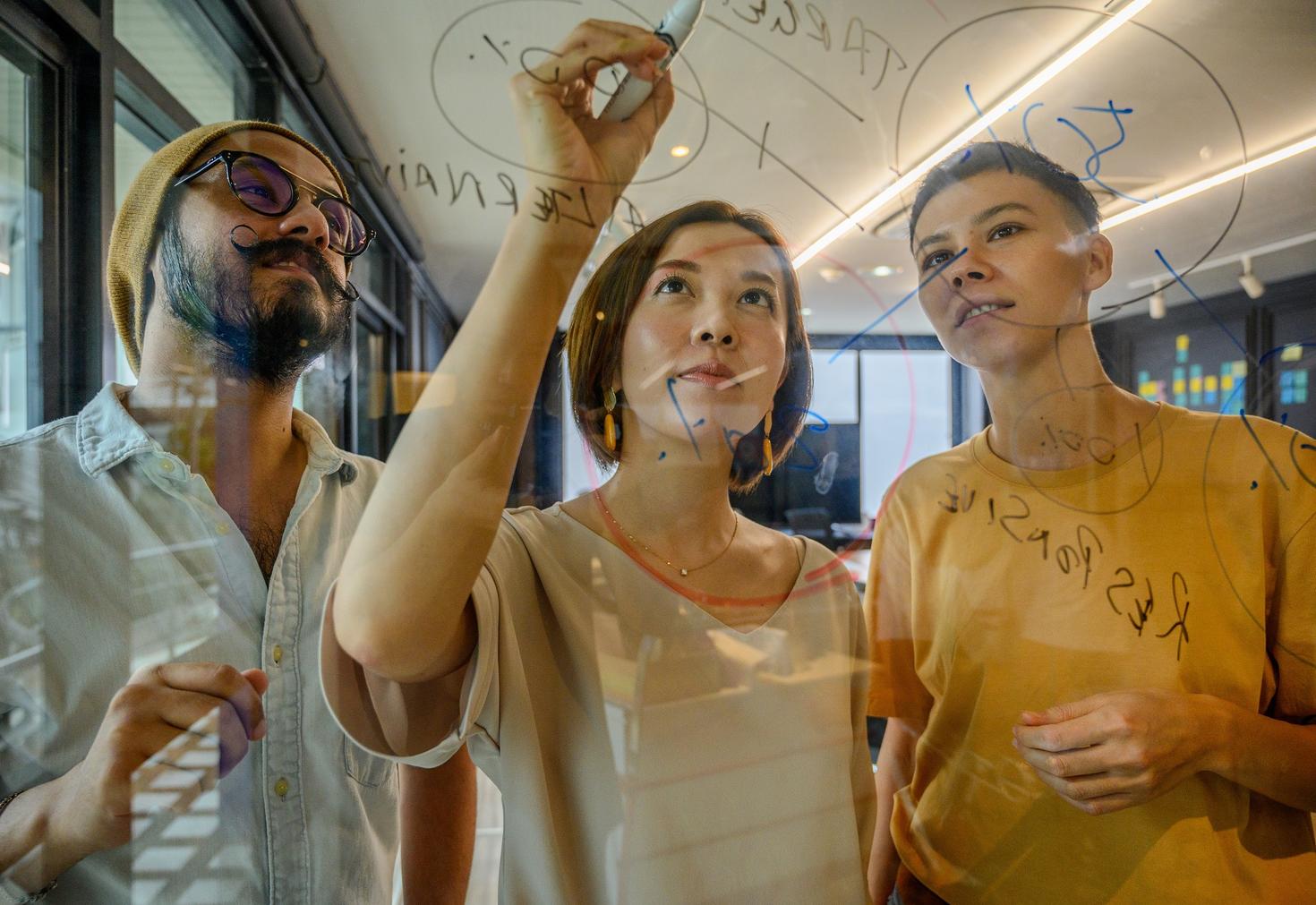 étudiants diplômés travaillant sur une solution sur un tableau en verre