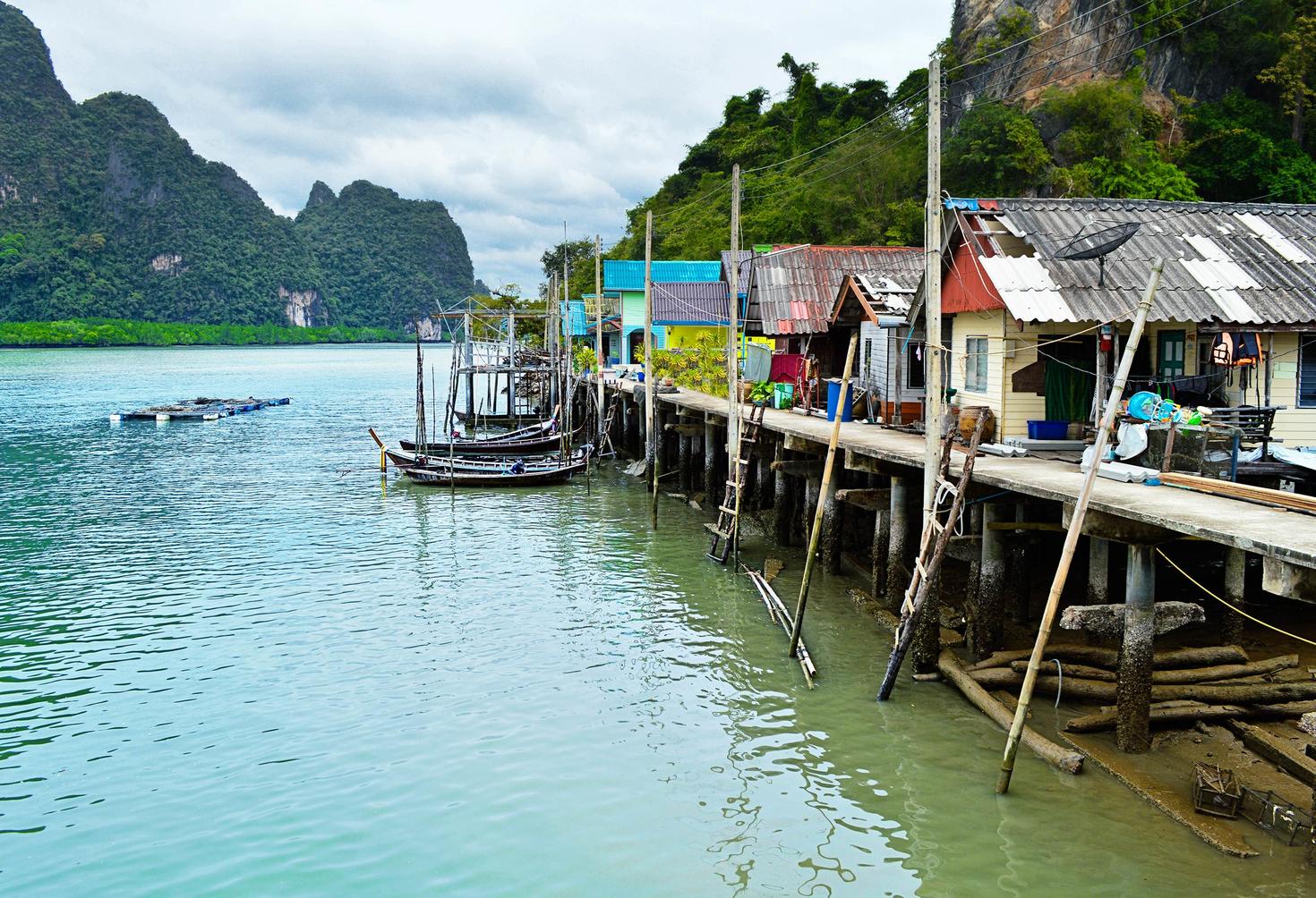 bateaux et des cabanes le long du rivage, des montagnes en arrière-plan