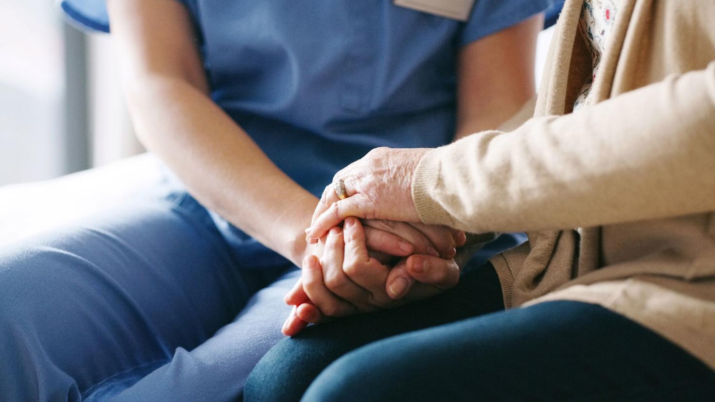 travailleur social tenant les mains d'une personne âgée