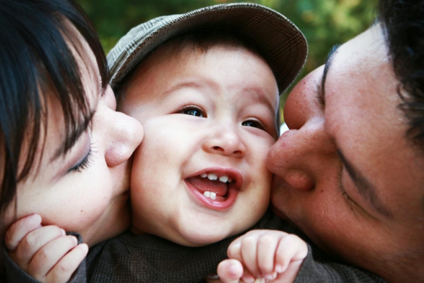 Parents kissing child's cheeks.