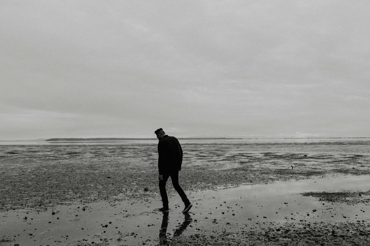 Homme marchant sur une plage, d'humeur maussade