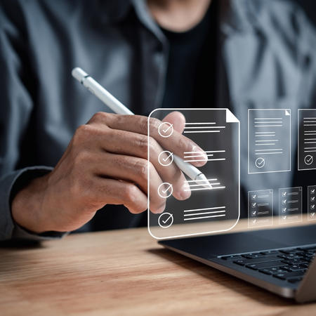 Une personne utilisant un Apple Pencil pour prendre des notes dans les airs devant un ordinateur portable. 