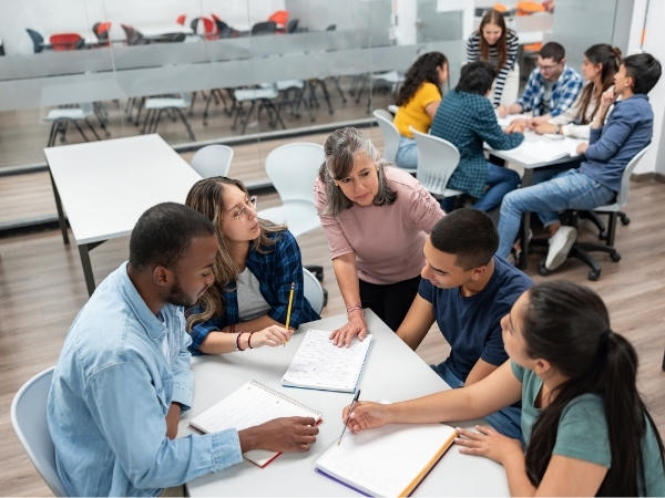 Deux groupes d'étudiants de troisième cycle travaillant à des tables dans une salle de classe.