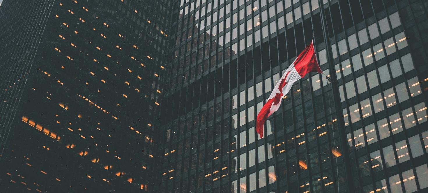 Le drapeau canadien flotte devant des immeubles commerciaux.