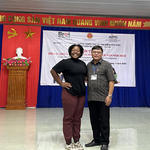 A photo of a student with an official in front of a vietnamese poster