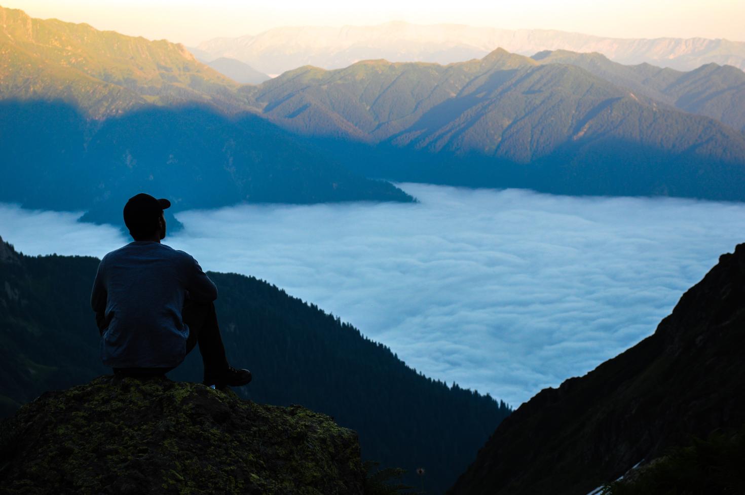 Personne assise au sommet d'une montagne