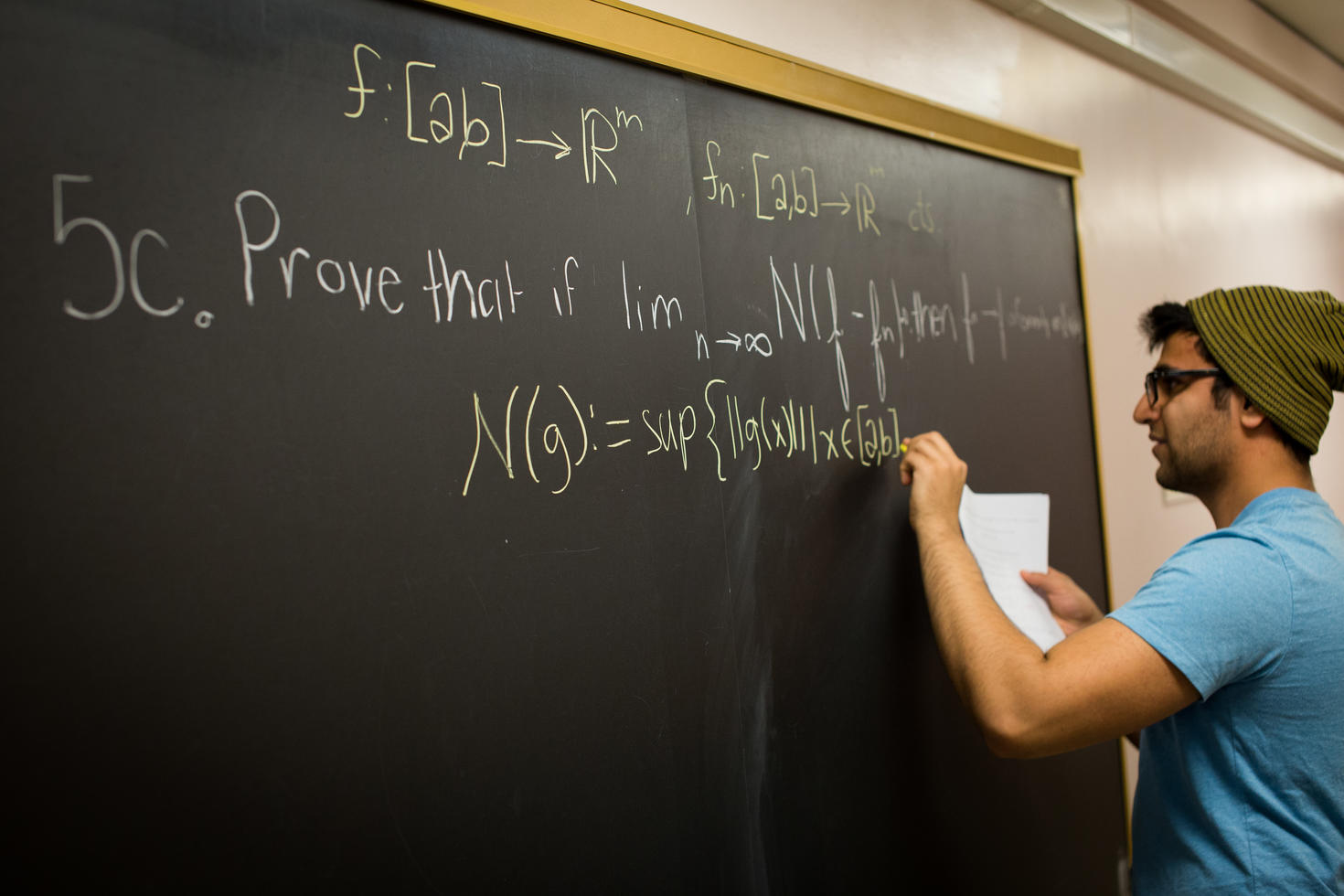 Étudiant diplômé écrivant des équations mathématiques sur un tableau noir