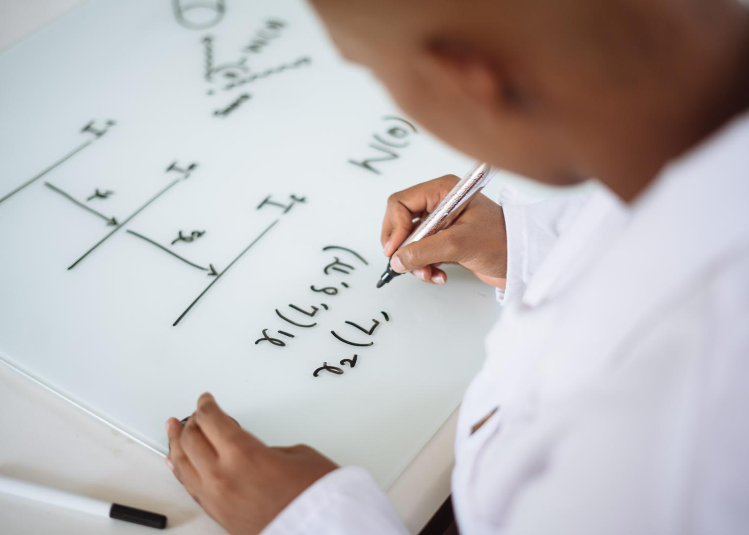 Etudiante écrivant des équations mathématiques sur un tableau blanc