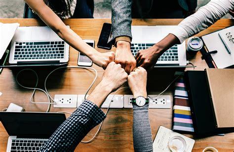 Réunion d'équipe avec des ordinateurs portables. Le personnel joignant les poings pour encourager l'équipe