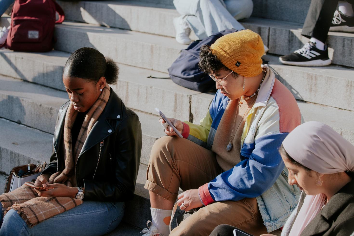 3 étudiants différents dans les escaliers du hall Tabaret, regardant sérieusement leurs téléphones