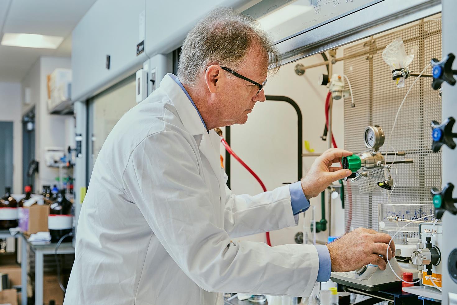 Le professeur Michael Organ, devant une hotte et manipulant l'équipement de chimie en flux.