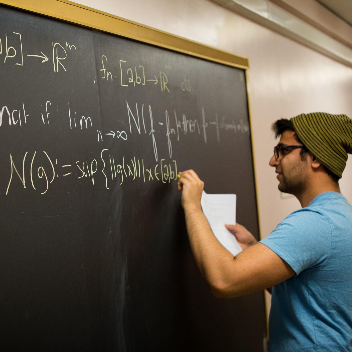 Étudiant écrivant une formule mathématique sur un tableau noir