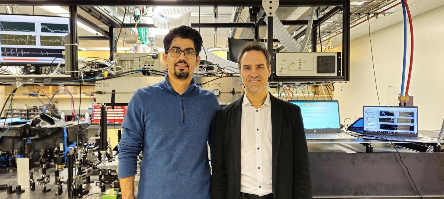 Le doctorant Ali Maleki (à gauche) et le professeur Jean-Michel Ménard (à droite) côte à côte dans un laboratoire laser, avec en arrière-plan des équipements optiques complexes, des écrans et des câbles.