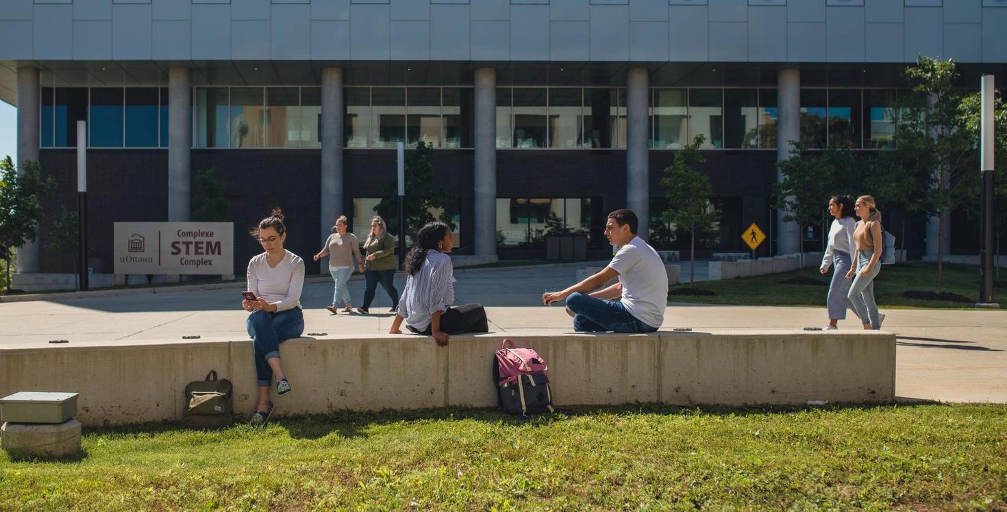 Étudiants assis et marchant devant le complexe STEM