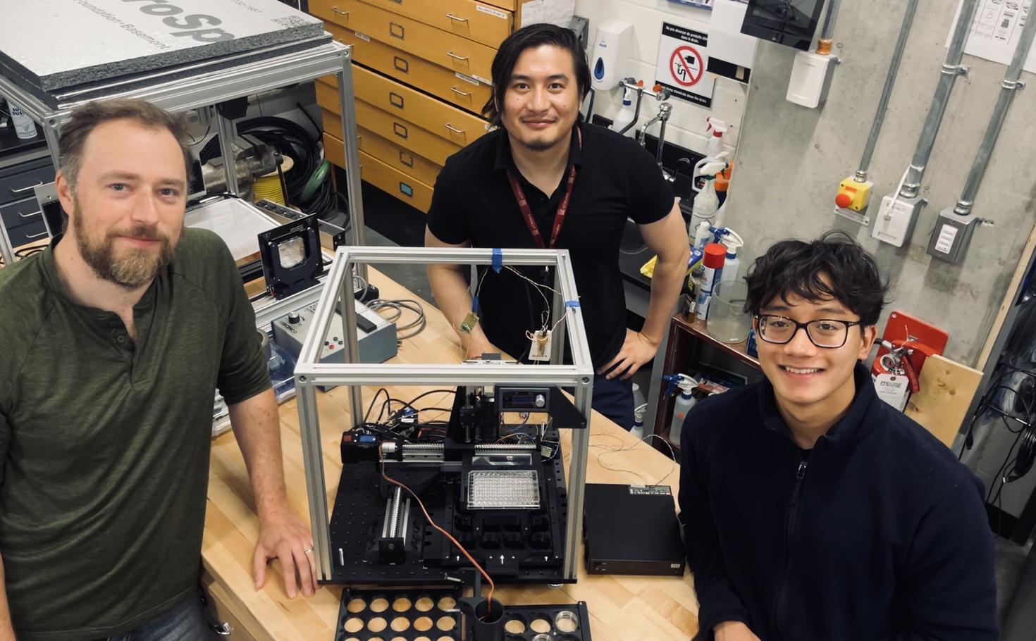 Lukasz Andrzejewski (technologue senior), Niepukolie Nipu (doctorante) et Huy Nguyen (étudiant de premier cycle bénévole dont Niepukolie est actuellement le mentor). Au centre se trouve le système automatisé à haute résolution et à haut débit que l'équipe développe pour surveiller le comportement et l'activité cardiaque des embryons et des larves de poissons zèbres.