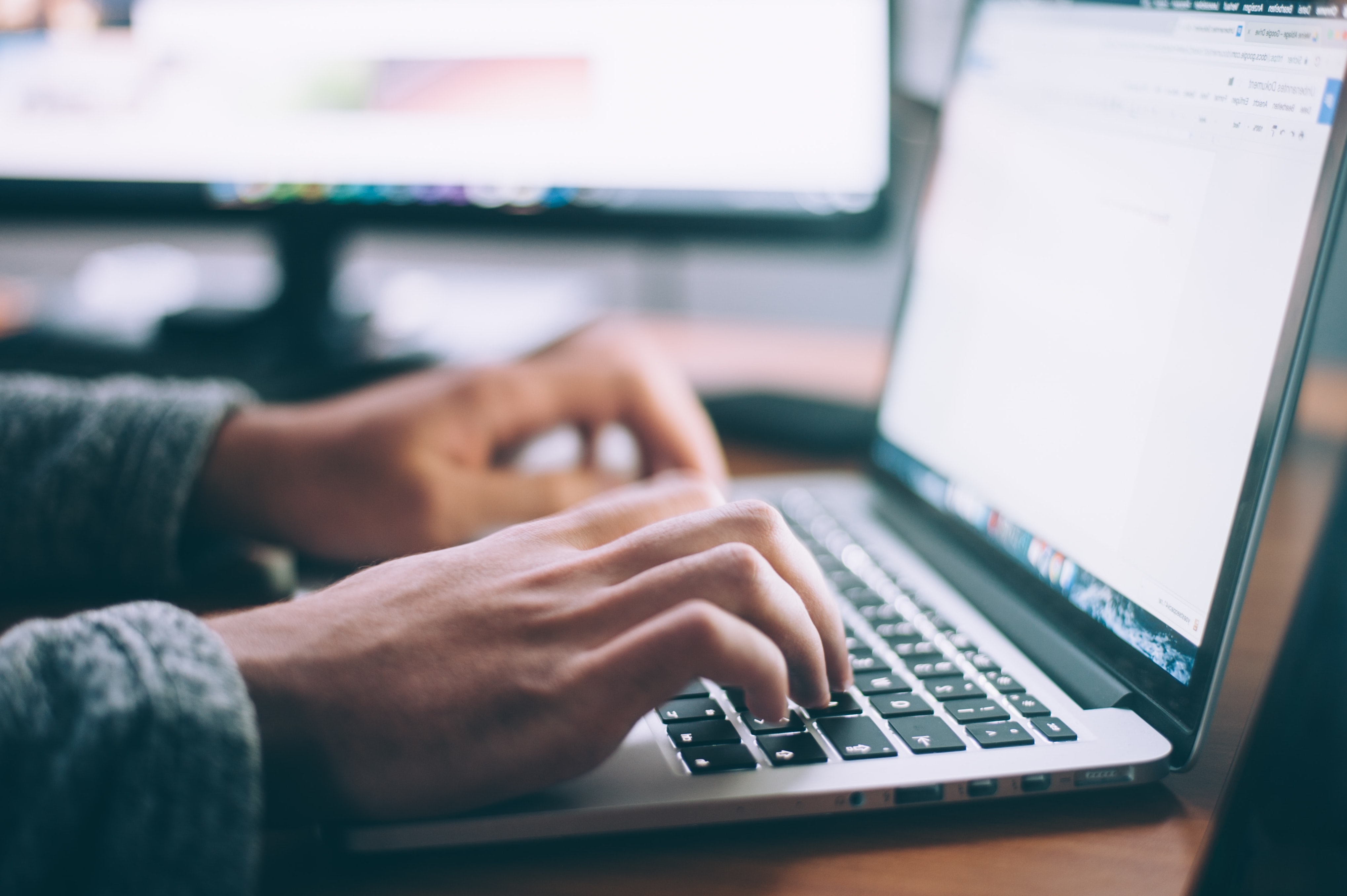 Hands typing on a laptop keyboard