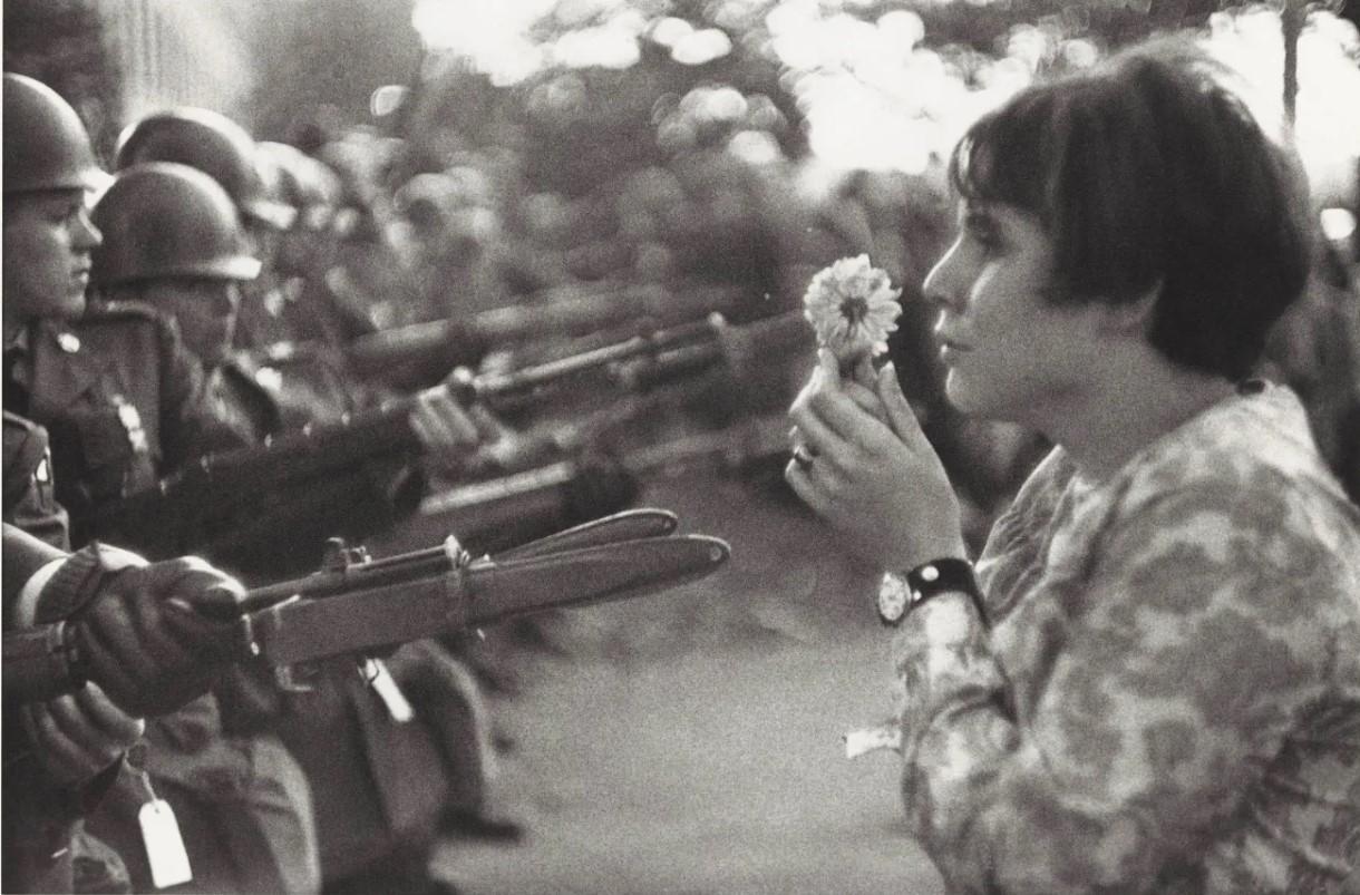 Marc Riboud, Jan Rose Kasmir holding a flower up to soldiers (October 21, 1967)