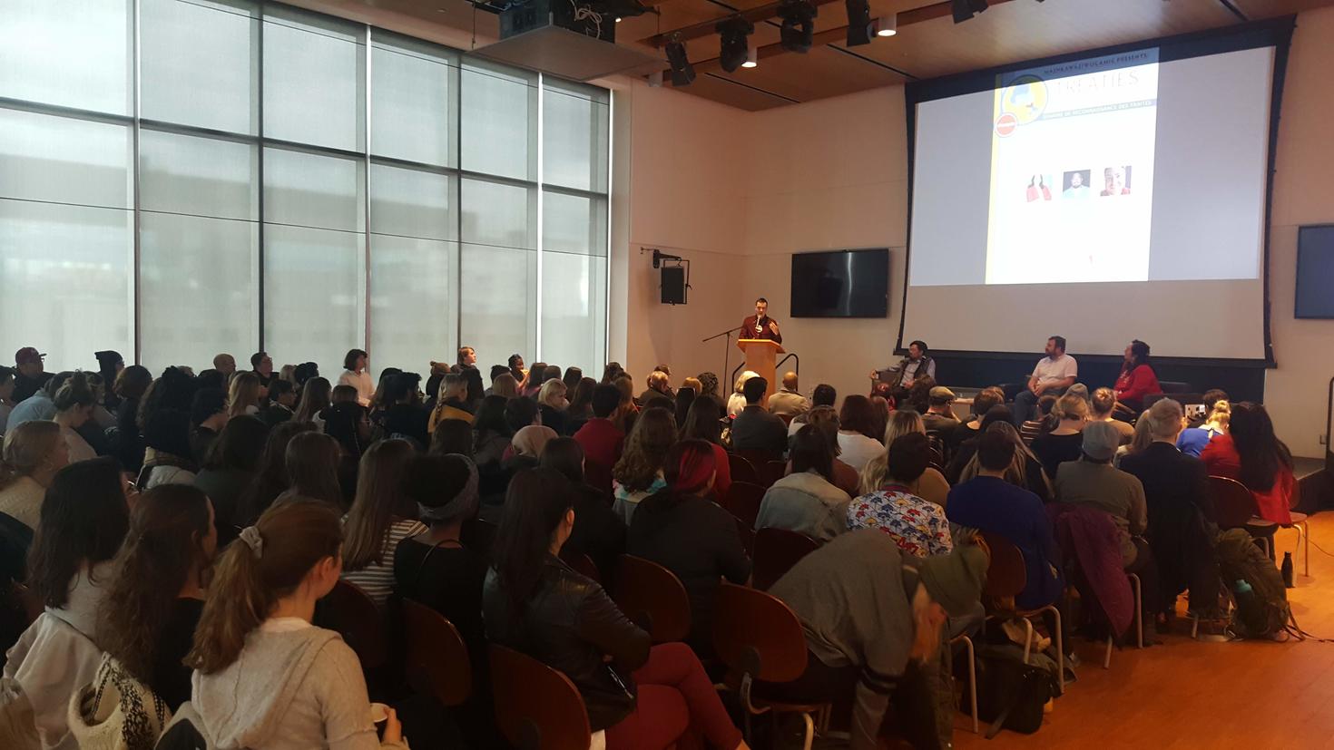 Room of audience members listening to someone giving a talk