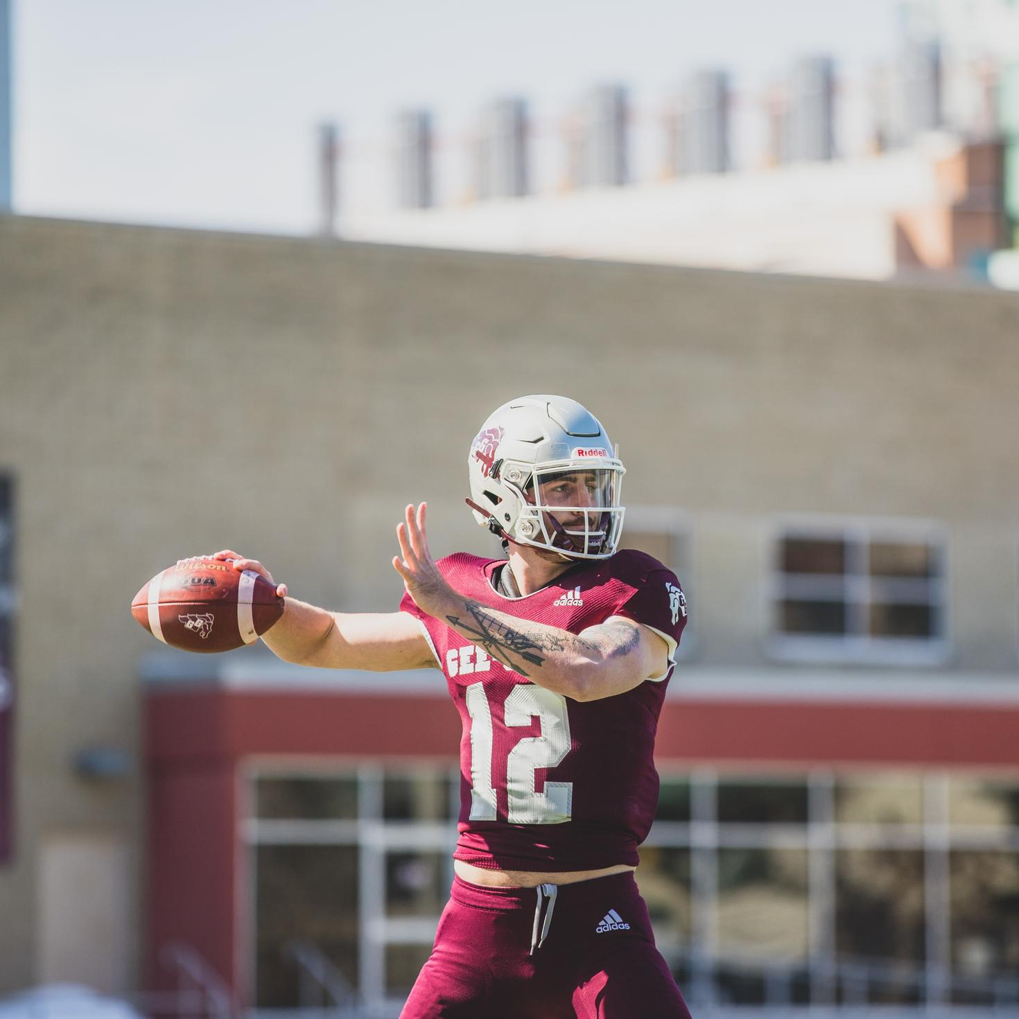 Indigenous student athlete in his football gear about to throw a football